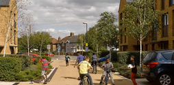 A group of children are playing outside in a residential area. Some are playing football and three are riding bikes.