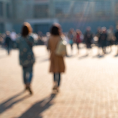 A blurred image shows two unidentifiable women walking away from us down a street.