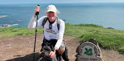 David Foster, an older caucasian man, kneeling on the grass at Lizard Point with his dog Pippin