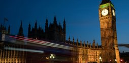 A shot of Big Ben at night time with a blurred double decker red bus moving past