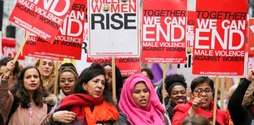 A group of women at the 'Million Women Rise' march. They look angry and powerful and are all holding signs that read 'Together we can end male violence against women'.