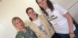 A photo of three smiling caucasian women, the one on the right is wearing a Rape Crisis tee-shirt